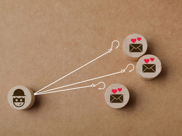 Three wooden pegs are clustered on the right, each with an envelope symbols and hearts over them. On the left is a wooden peg with a burglar symbol on it. Lines with hooks reach out to the envelopes. Meant to convey the danger of online romances when you don't have a clear idea of the identity of the person romancing you.